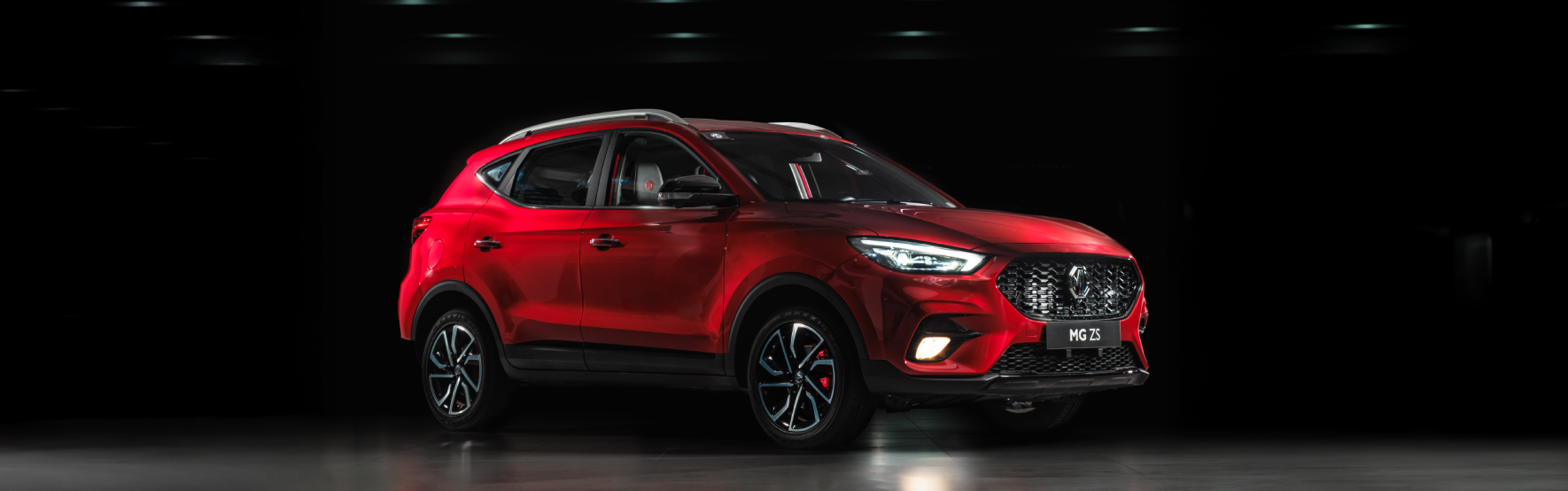 Image of three-quarter view of red MG ZS against a dark background.