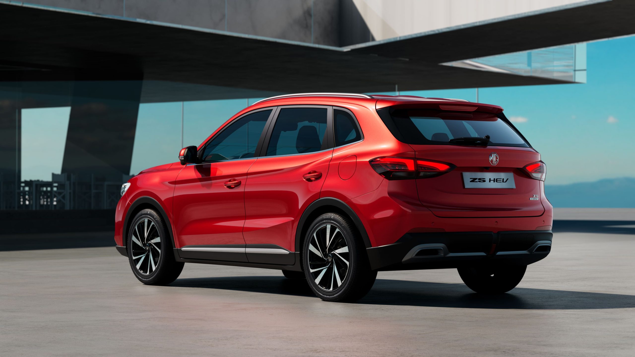 Rear view of the MG ZS Hybrid+ in red, showcasing its sleek SUV design, LED taillights, aerodynamic curves, and modern rear bumper styling